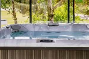 Jacuzzi na tarasie z widokiem na zieloną scenerię za szybą