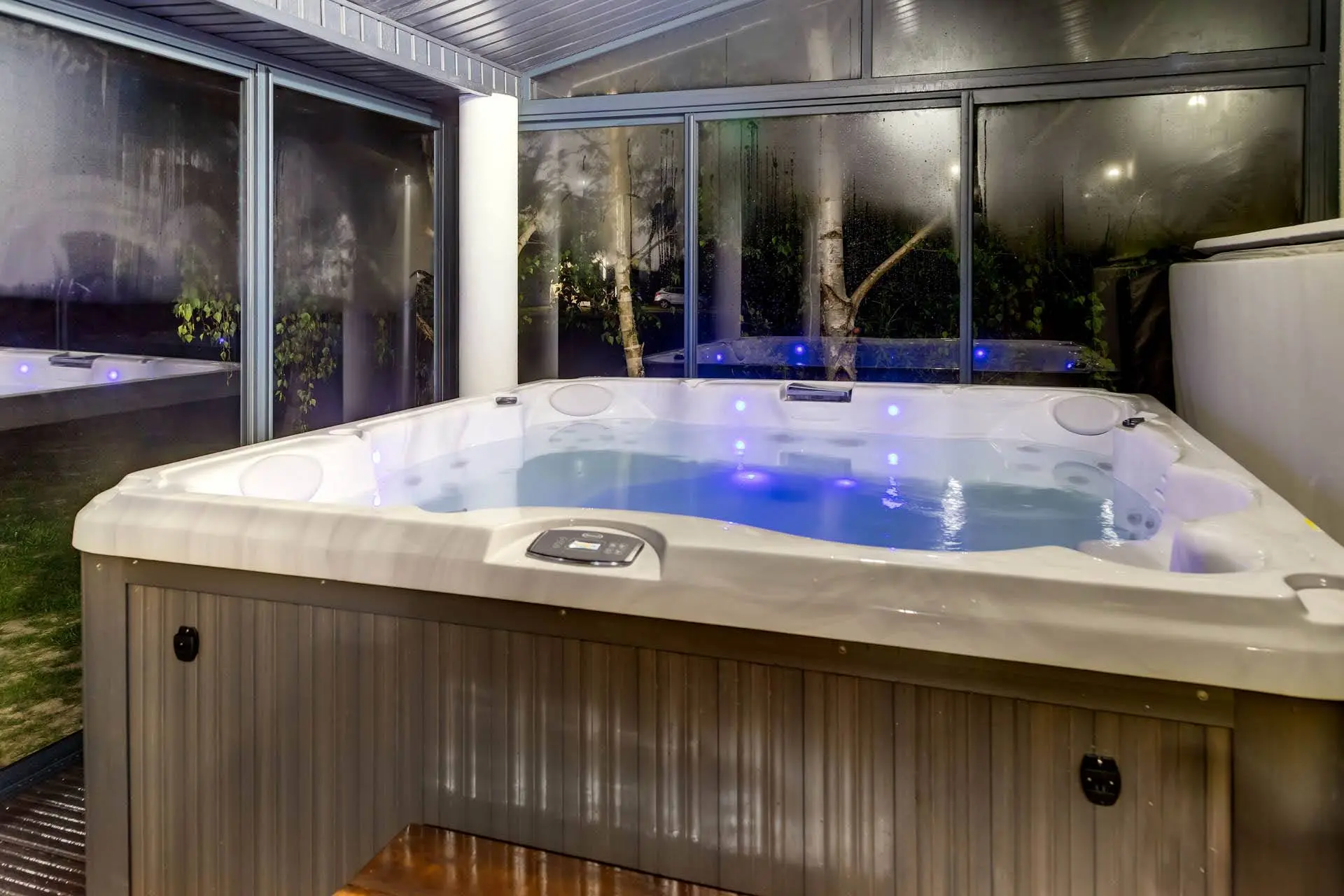 Jacuzzi w przeszklonym mini spa nocą z podświetleniem LED