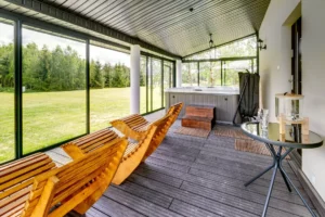 Strefa relaksu z leżakami i stołem na przeszklonym tarasie domku spa
