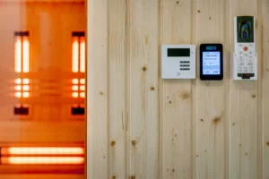 Sterowniki i panel sterowania sauną infrared na drewnianej ścianie